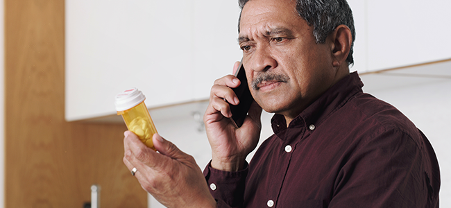 Man on phone looking at unmarked bottle of medication