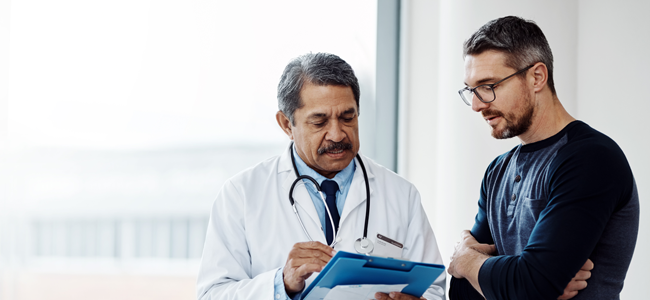 Older man with glasses looking at pill bottle.