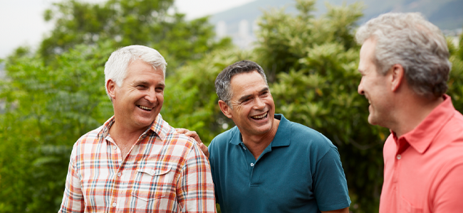 3 men standing together smiling at each other.