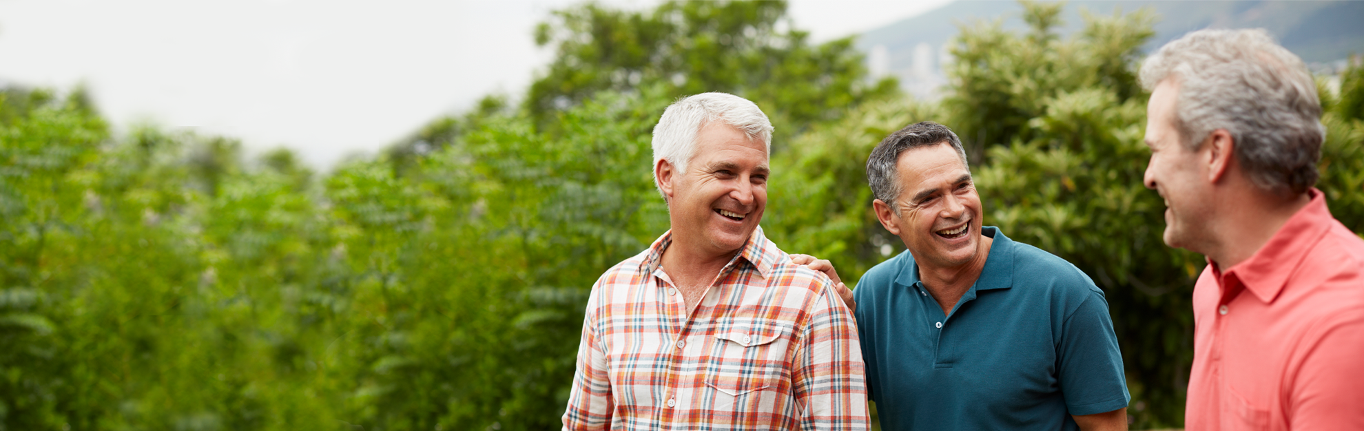 Three happy men smiling at each other.